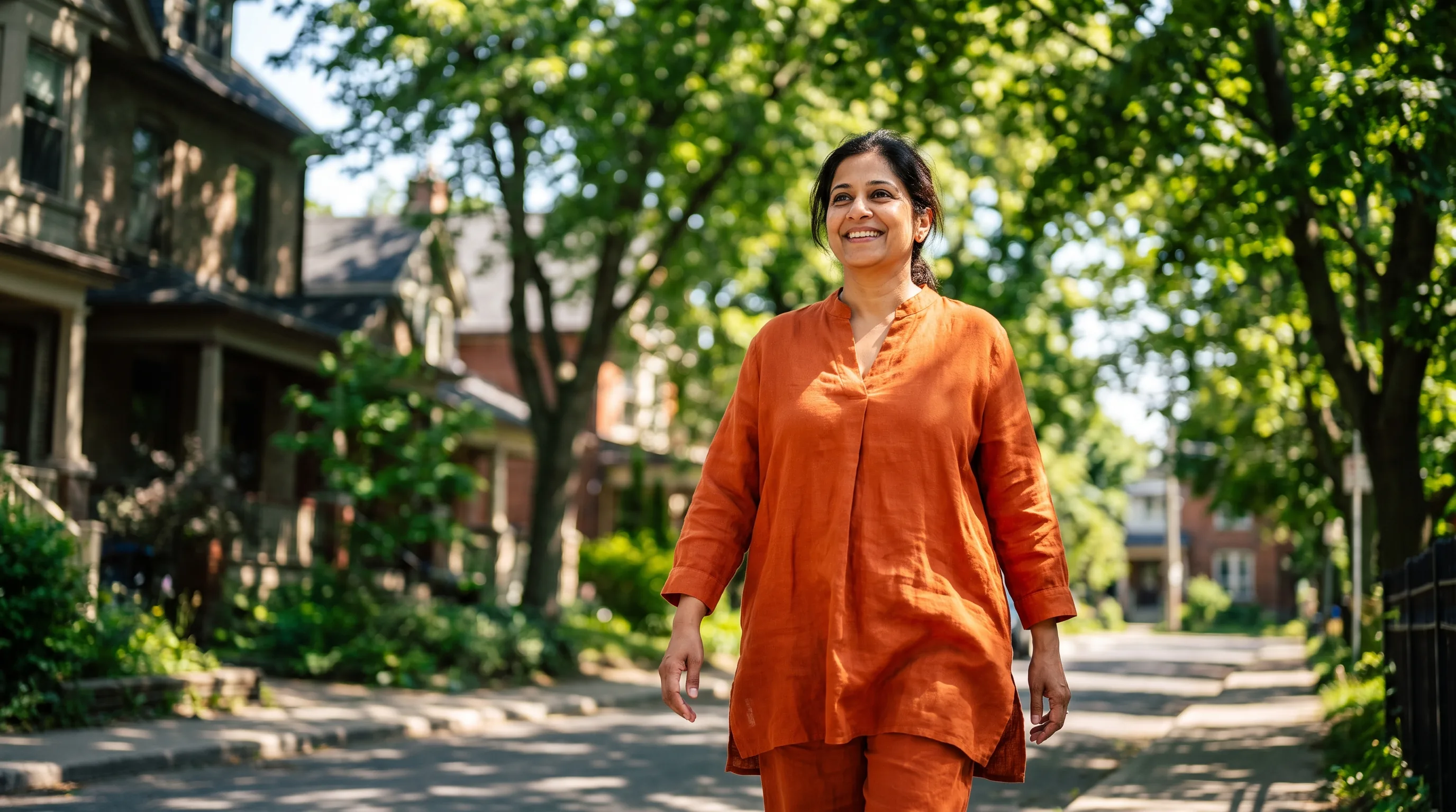 A woman in her forties on a bright morning walk through a leafy neighborhood, relaxed and unhurried, her mind clearly not on food