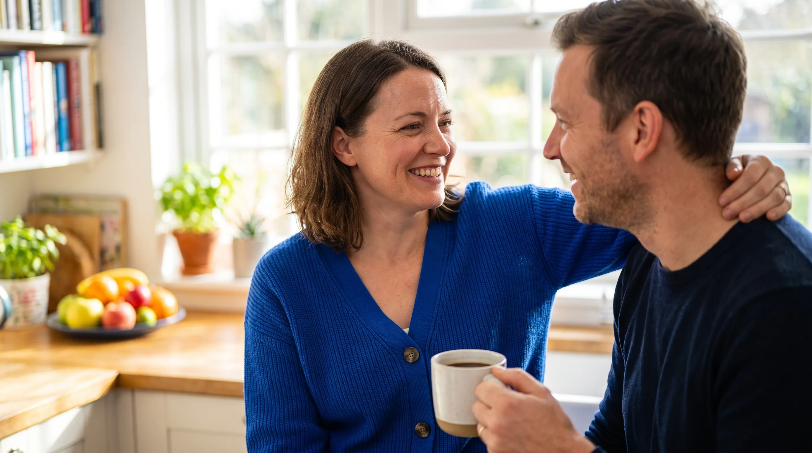 A confident, healthy couple in their late 30s sharing a warm, relaxed morning at home, close and at ease together, natural light, tasteful and non-explicit