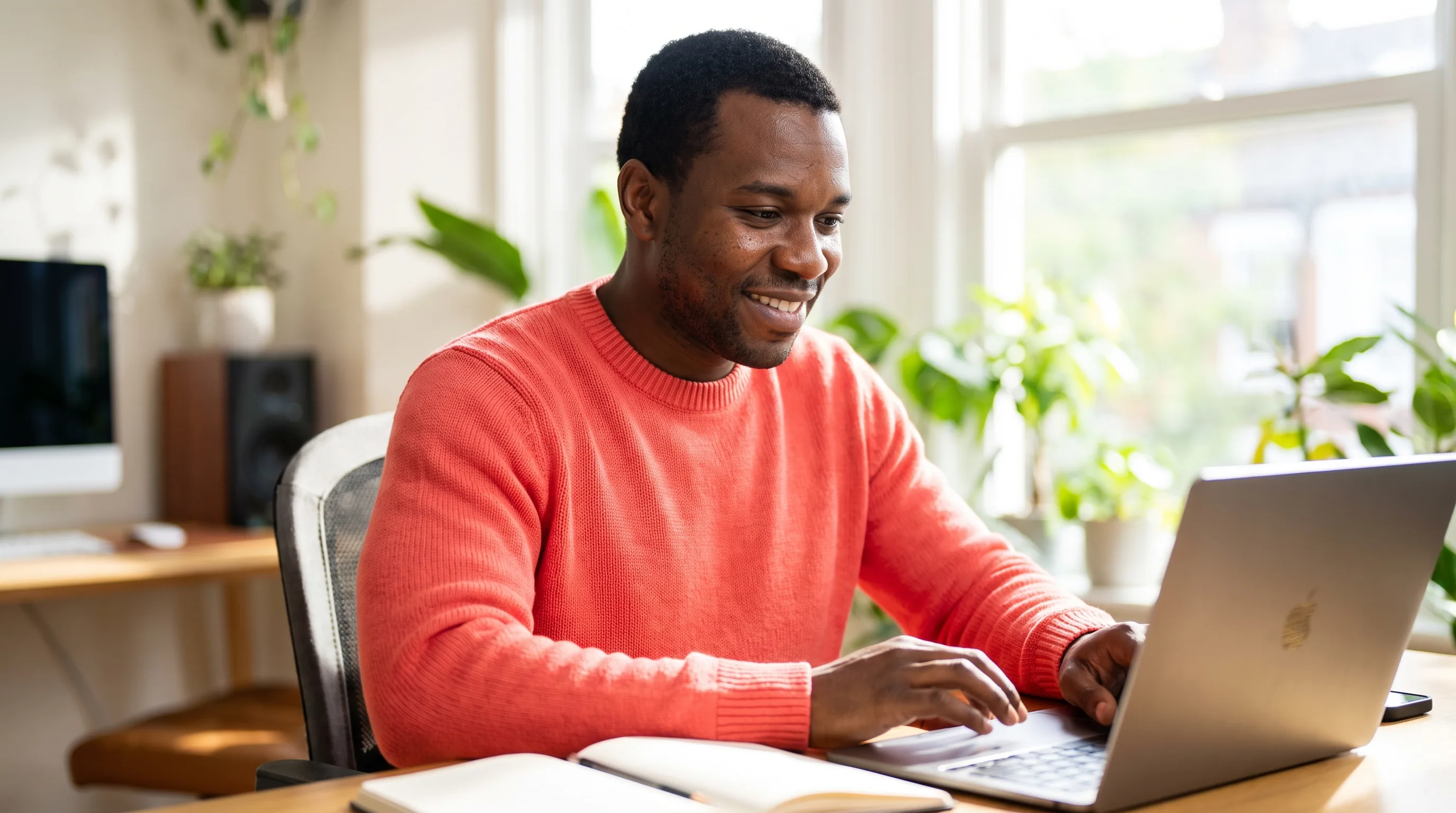 A focused young professional working calmly at a sunlit desk with a clear, unhurried expression