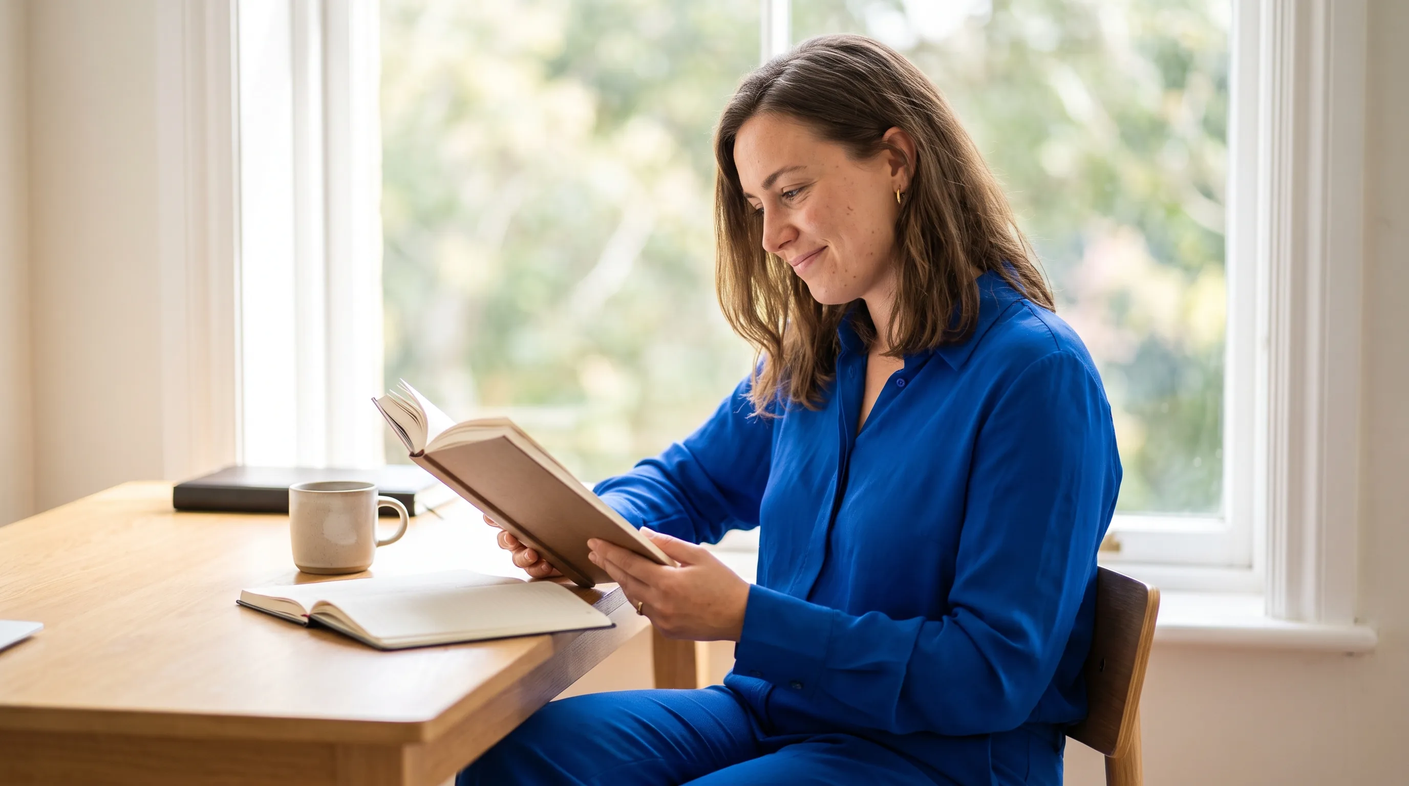 A focused knowledge worker reading calmly at a tidy desk by a bright window, clear-headed and unhurried